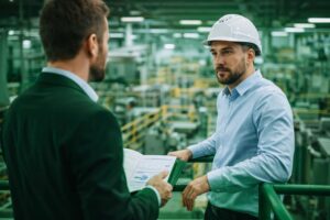 Ingeniero industrial conversando con un responsable de selección en una planta, valorando una oportunidad profesional en un entorno técnico e industrial.